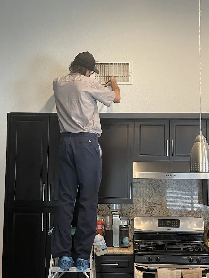 Technician inspecting an air vent during HVAC service in Williston Park